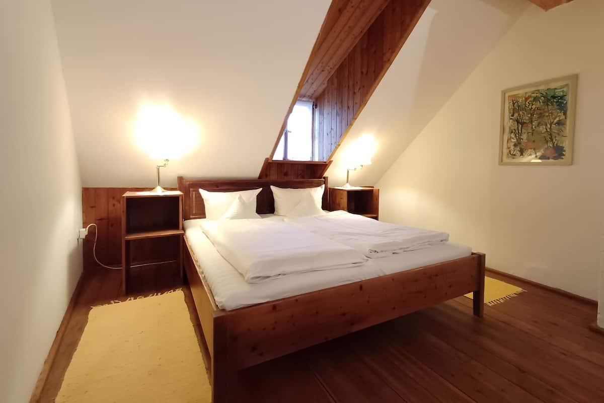 Ein Schlafzimmer mit einem hölzernen Bett, zwei Nachttischen mit Lampen, einer Holzzahlende und einem Gemälde an der Wand.