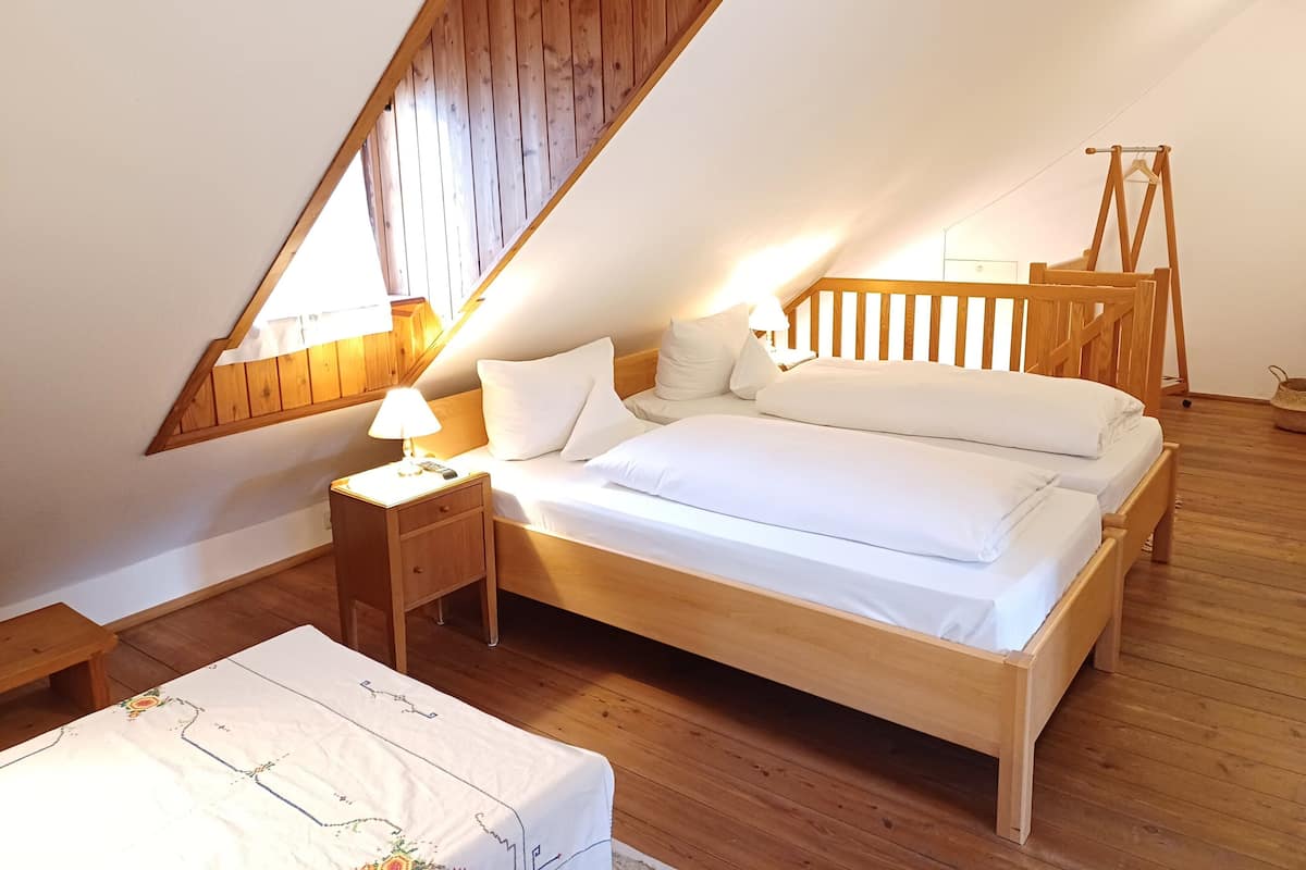 Ein gemütliches, helles Schlafzimmer mit einem hölzernen Bett, einem Nachttisch mit Lampe und einem Holzschrank.