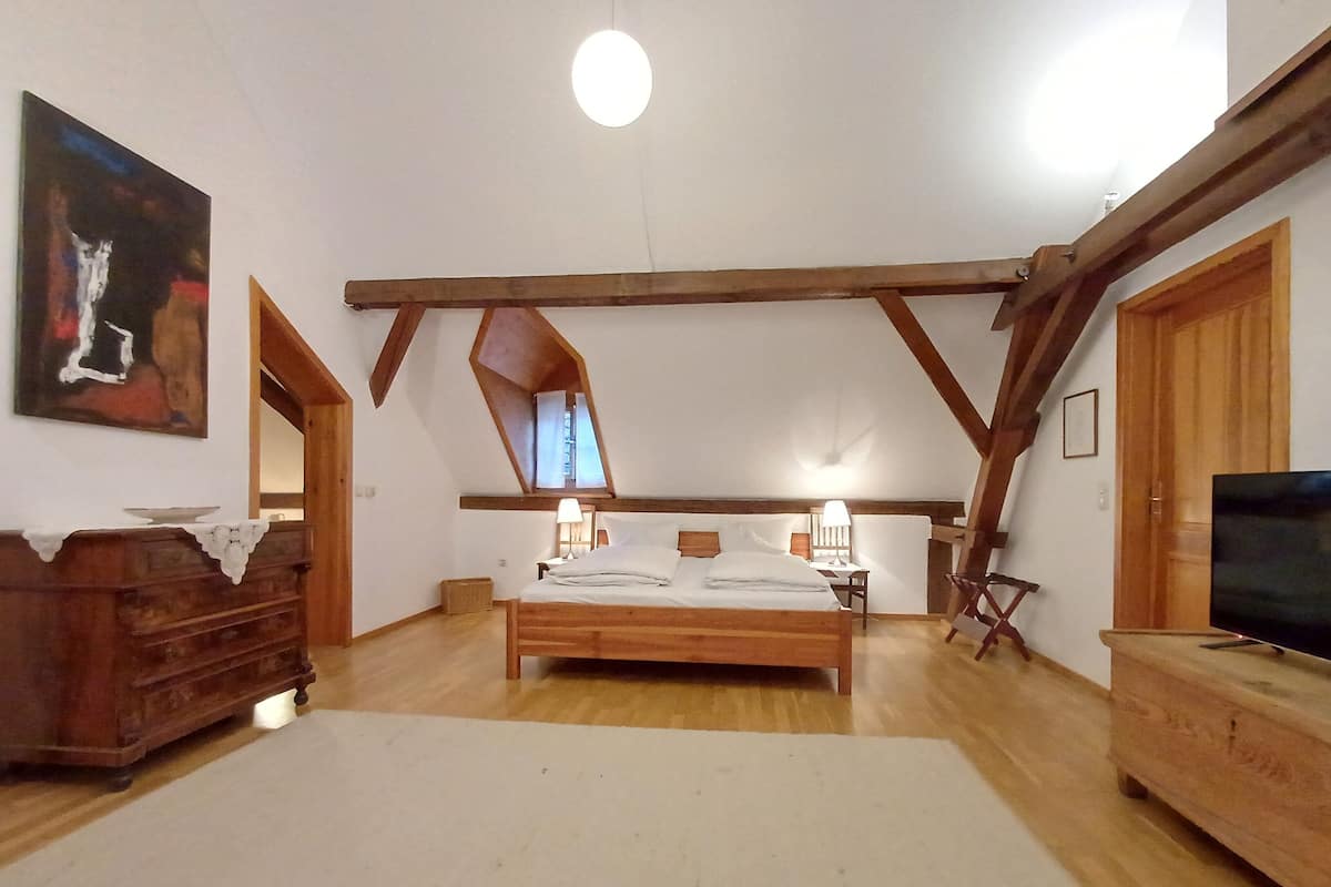 Ein Schlafzimmer mit einem hölzernen Bett, zwei Nachttischlampen, einem Fernseher und einem Gemälde an der Wand.