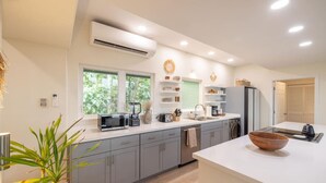 A modern kitchen with grey cabinets, a white countertop, and a large window. - Kona Sunset Retreat | Walk to Shops & Dining (Kailua-Kona)