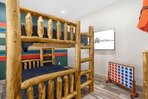 Una cama litera con estructura de madera y una pared de fondo a rayas coloridas.