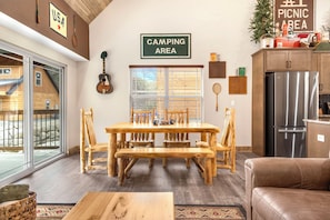 Una mesa de comedor de madera con sillas, un refrigerador y un letrero que indica un área de camping.