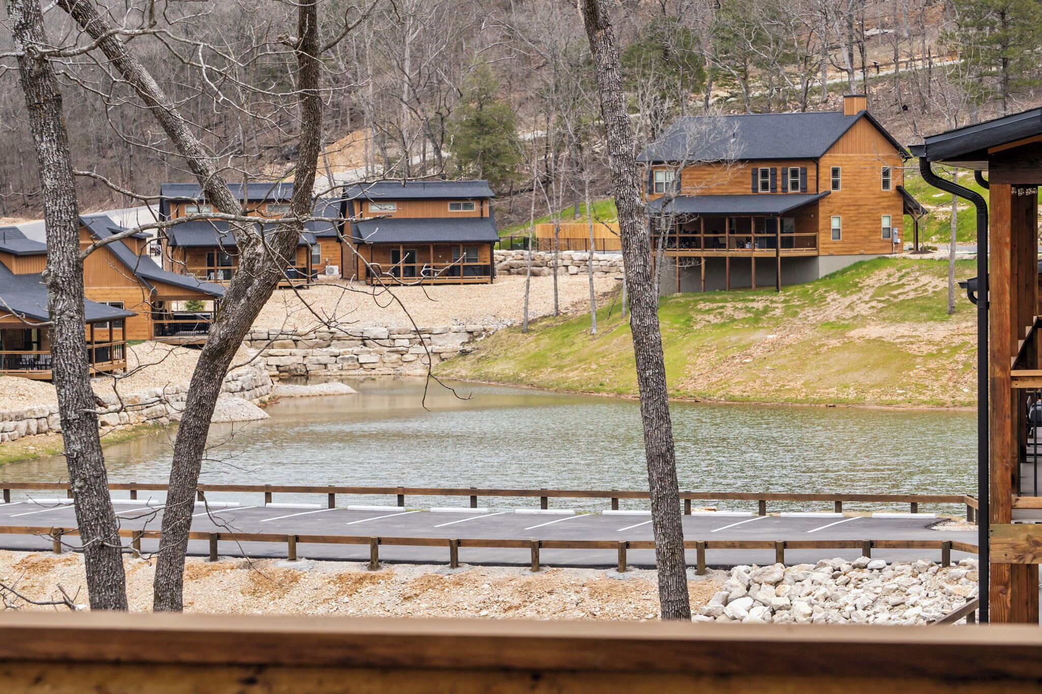 A lakeside lodge with multiple wooden cabins, a dock, and a stone pathway leading to the water.