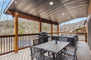 Um deck externo com churrasqueira, assentos e uma mesa.