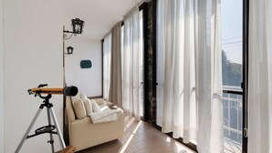 A balcony with a sofa, curtains, a telescope, and a wall-mounted light fixture. - Villa 'Ca' D'Ros Pool and Sauna' with Mountain View, Private Pool and Wi-Fi (Fontanile)