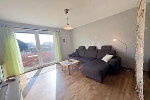 En moderne stue med en grå sofa, et træsofabord og en gulvlampe.
