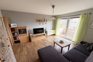 En stue med sofa, fjernsyn, træskab og et bord med en skål fyldt med sten.