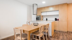 A compact kitchen with a central island, wooden cabinets, and a stainless steel range hood. - GuestReady - Ceuta Axis Awaits (Porto)