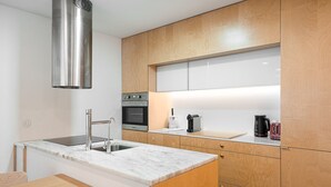 A compact kitchen with a stainless steel range hood, a built-in oven, and a coffee maker on the countertop. - GuestReady - Ceuta Axis Awaits (Porto)