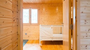 Een kamer met houten lambrisering, een ledikantje en een raam.