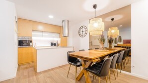 Een moderne keuken met houten kastjes, een inbouwoven en een eethoek met een houten tafel en stoelen.