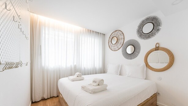 Een moderne hotelkamer met een groot bed, witte lakens en decoratieve wandkunst.