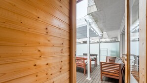 Een houten interieur met uitzicht op een terras met een tafel en stoelen.