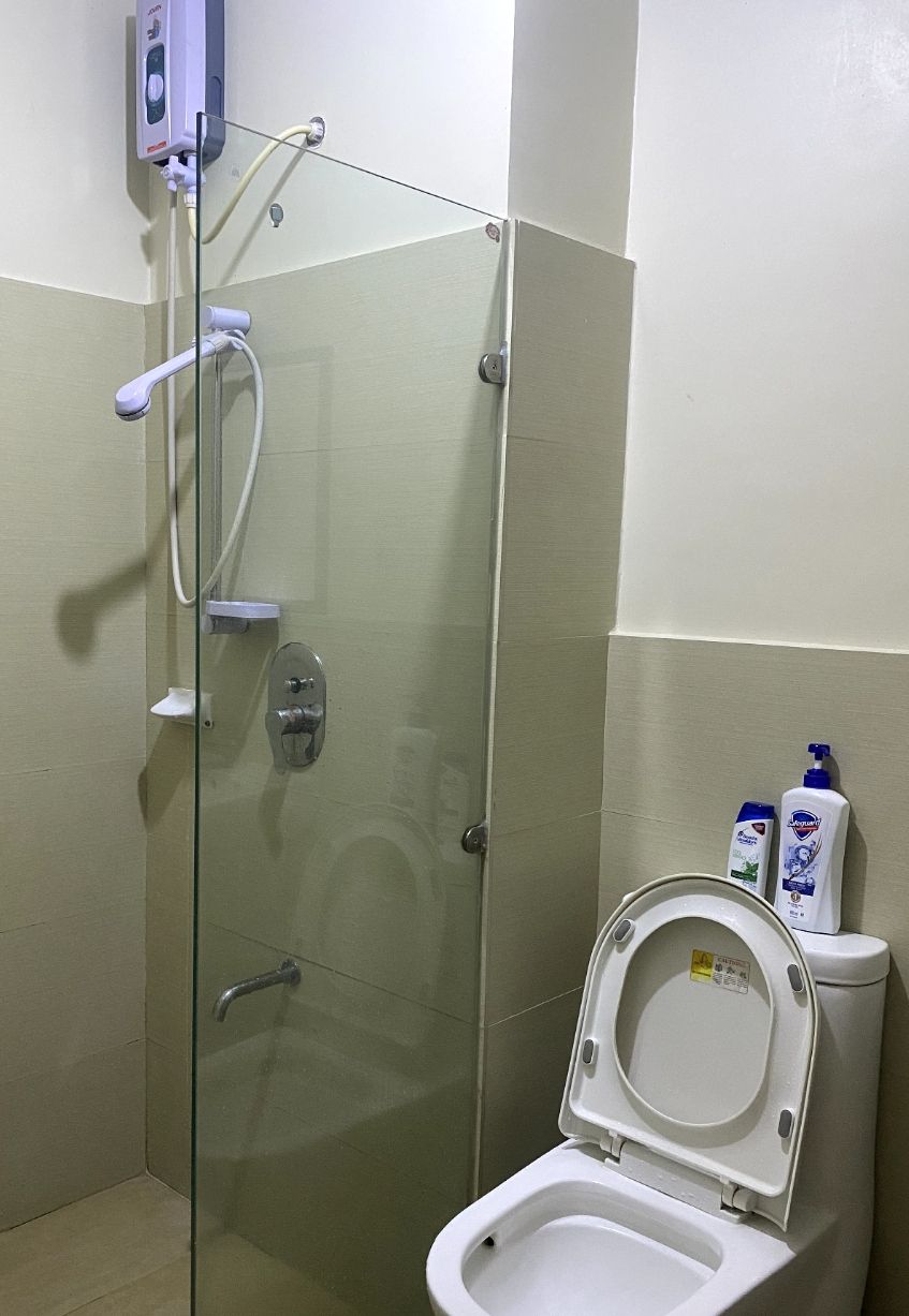 A glass-enclosed shower stall with a toilet adjacent to it, both with white fixtures.