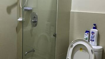 A glass-enclosed shower stall with a toilet adjacent to it, both with white fixtures.