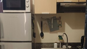 A compact kitchen with a built-in microwave and a refrigerator.