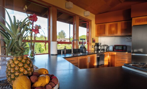 Una cocina moderna con armarios de madera, un ventanal grande y un frutero en la encimera.