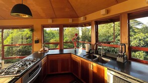 Eine moderne Küche mit Holzschränken, einem Gasherd, einer Spüle und einem Fenster mit Blick auf Grünflächen.