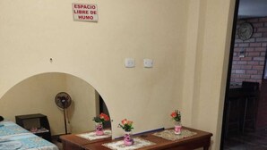A hotel room with two beds, a wooden table with a lace tablecloth, and a sign indicating a free space.