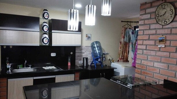 A modern kitchen with a black countertop, stainless steel appliances, and pendant lights.