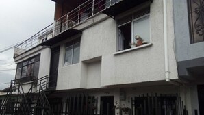 A two-story residential building with a balcony, a gated entrance, and a visible door.