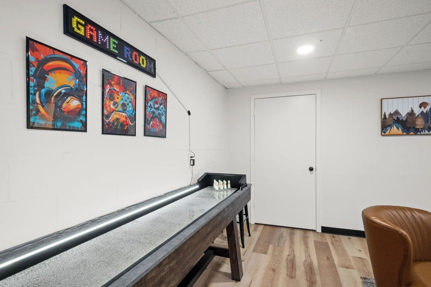 A room with a long, narrow table, a door, and three colorful abstract paintings on the wall.