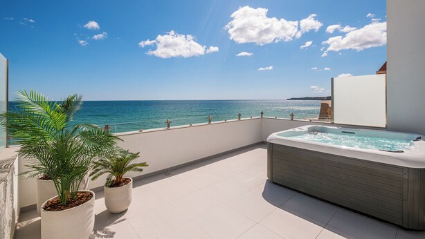 A balcony with a hot tub, potted plants, and a view of the sea. - Sob O Mar II - Stunning beach/sea view (Armação de Pêra)