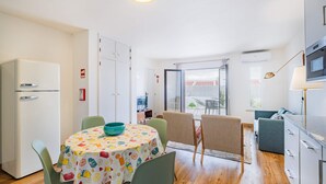 A compact kitchen with a dining area, a refrigerator, a microwave, and a table with chairs. - Stanchion Apartment (Albufeira)