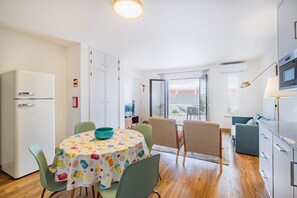 A compact kitchen with a dining area, a refrigerator, a microwave, and a table with chairs.