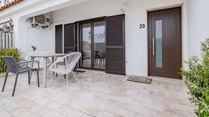 A building with a number 20, a covered patio with chairs and a table, and a door with a handle. - Stanchion Apartment (Albufeira)