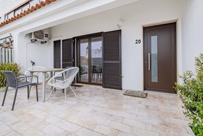 A building with a number 20, a covered patio with chairs and a table, and a door with a handle.