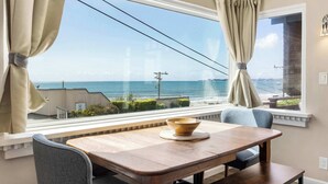 A dining area with a view of the sea, a wooden table, and two chairs. - Adorable Rio Del Mar Beach House - Steps to beach! (Aptos)