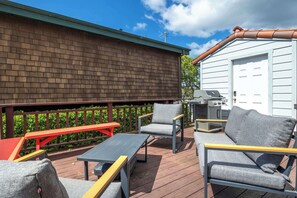 Une terrasse extérieure avec un plancher en bois, un barbecue et du mobilier d’extérieur comprenant des chaises et une table.