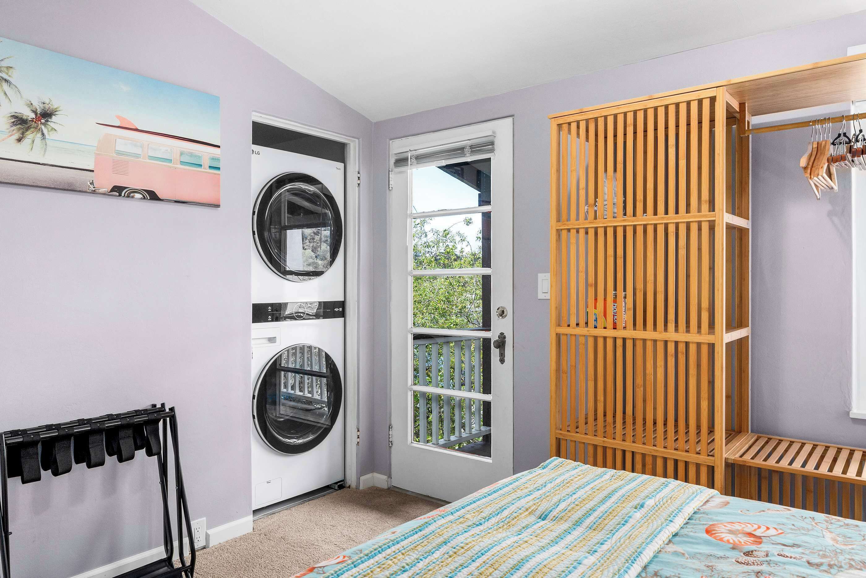Ein Schlafzimmer mit einem Bett, einem Holzschrank, einer Waschmaschine und einer Tür, die auf einen Balkon führt.