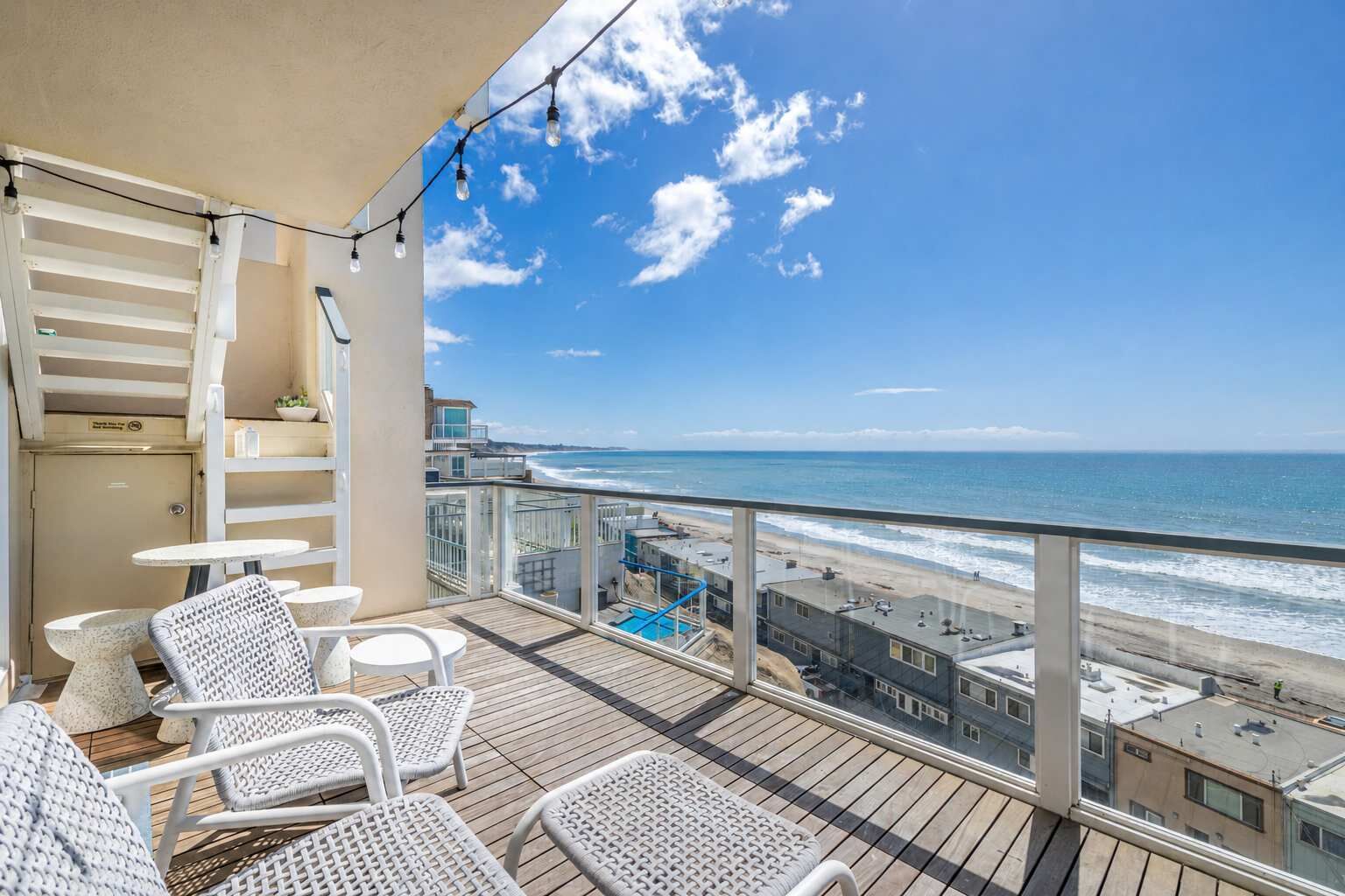 Un balcon avec vue sur la plage, une piscine et le paysage urbain.