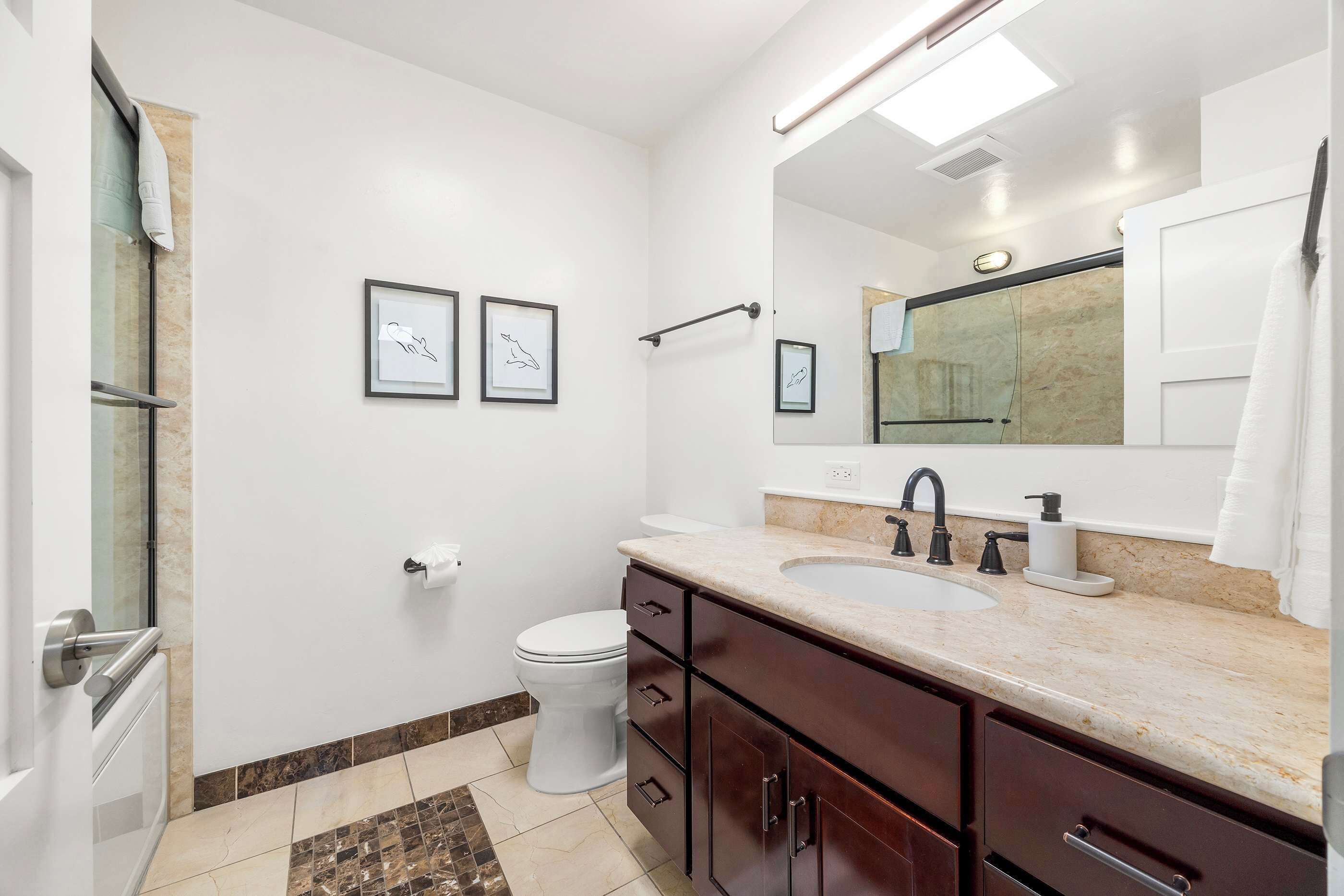 Un baño moderno con lavamanos, espejo e inodoro.
