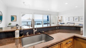 Una cocina moderna con un lavamanos grande, vista al mar y un comedor con vistas.