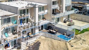 Un edificio de varios pisos con balcones, grandes ventanales y una zona de piscina.