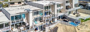 Un immeuble à plusieurs étages doté de balcons, de grandes fenêtres et d’un espace piscine.