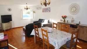 A cozy living room with a TV, sofa, and dining area with chairs and a table. - Air-conditioned holiday villa 3 bedrooms sea view (CAVALAIRE SUR MER)