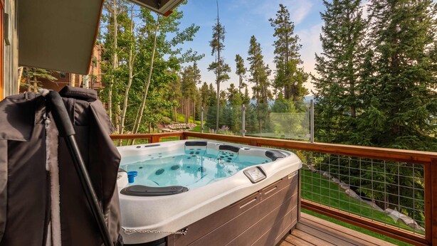 Ein Whirlpool auf einer Holzterrasse mit Blick auf hohe Bäume.