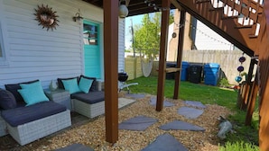 Un patio cubierto con mobiliario exterior, una pérgola y un camino de jardín.