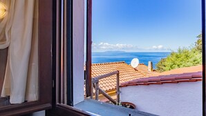 A view from a window overlooking a coastal area with a clear sky, a satellite dish, and a tiled roof. - Villa with swimming pool and sunset view (Marciana Marina)