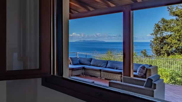 A room with a view of the sea, a wicker sofa, and a wooden ceiling. - Villa with swimming pool and sunset view (Marciana Marina)