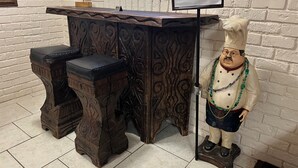 A rustic wooden counter with a sign that reads "Laissez les bons temps rouler!" and a statue of a chef with a cane.
