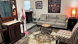 A living room with a leather sofa, patterned rug, wooden cabinet, and a decorative statue.