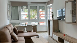 Una sala de estar moderna con un sofá, una mesa de centro, un televisor y un comedor con sillas y una mesa.