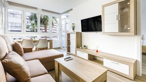 Una sala moderna con sofá, mesa de centro, televisor y un amplio mueble de madera.