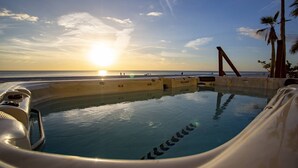 A hot tub with a view of the sunset over the ocean.