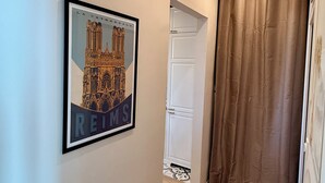 A hallway with a framed picture of a cathedral, a white door, and a brown curtain. - THE REMOISED ECRIN (Reims)